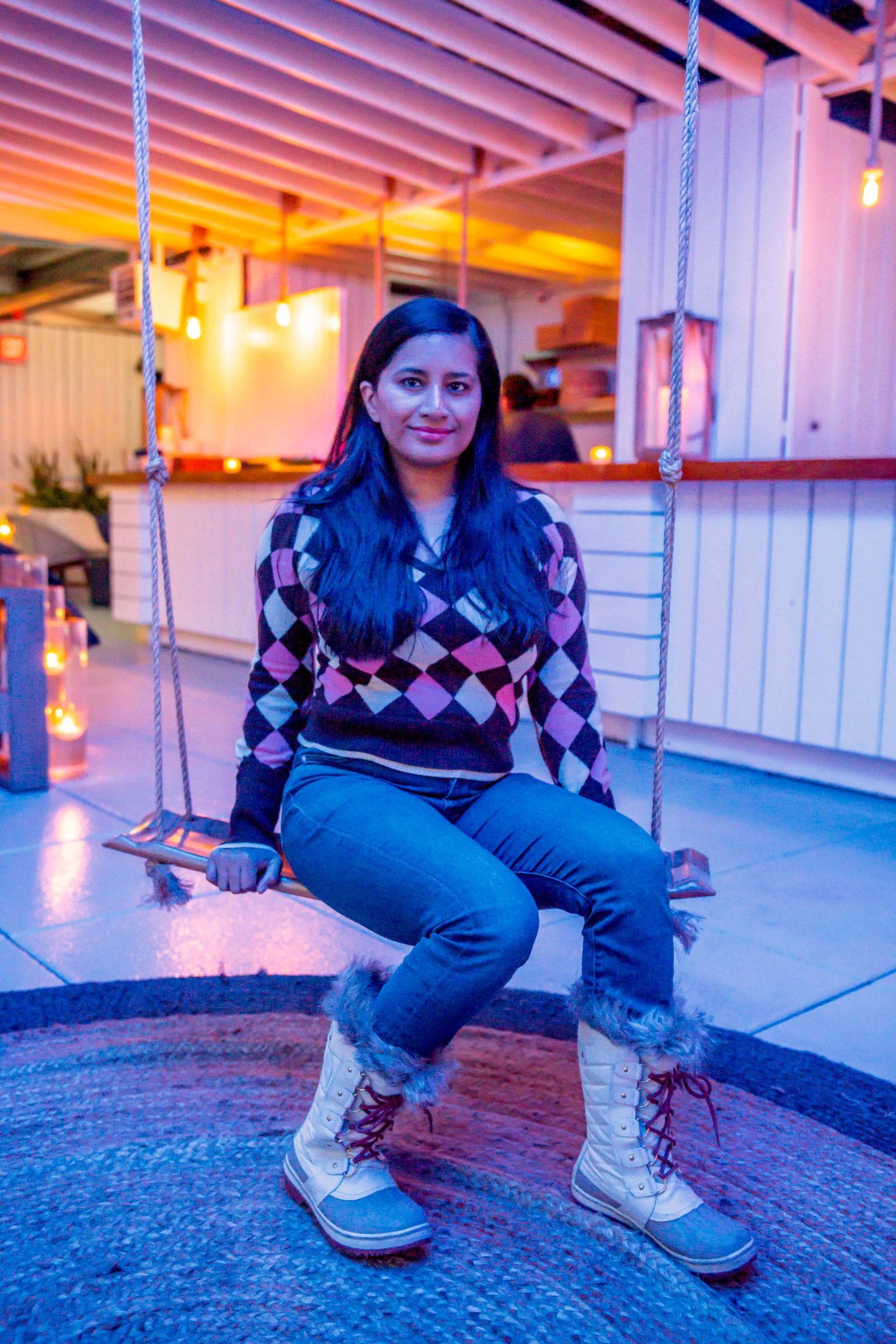 The Best Winter Rooftop Bars in NYC in 2022: Sandbar Sandbar woman on swing. Best Winter Rooftop Bars in NYC. Sandbar Rooftop.