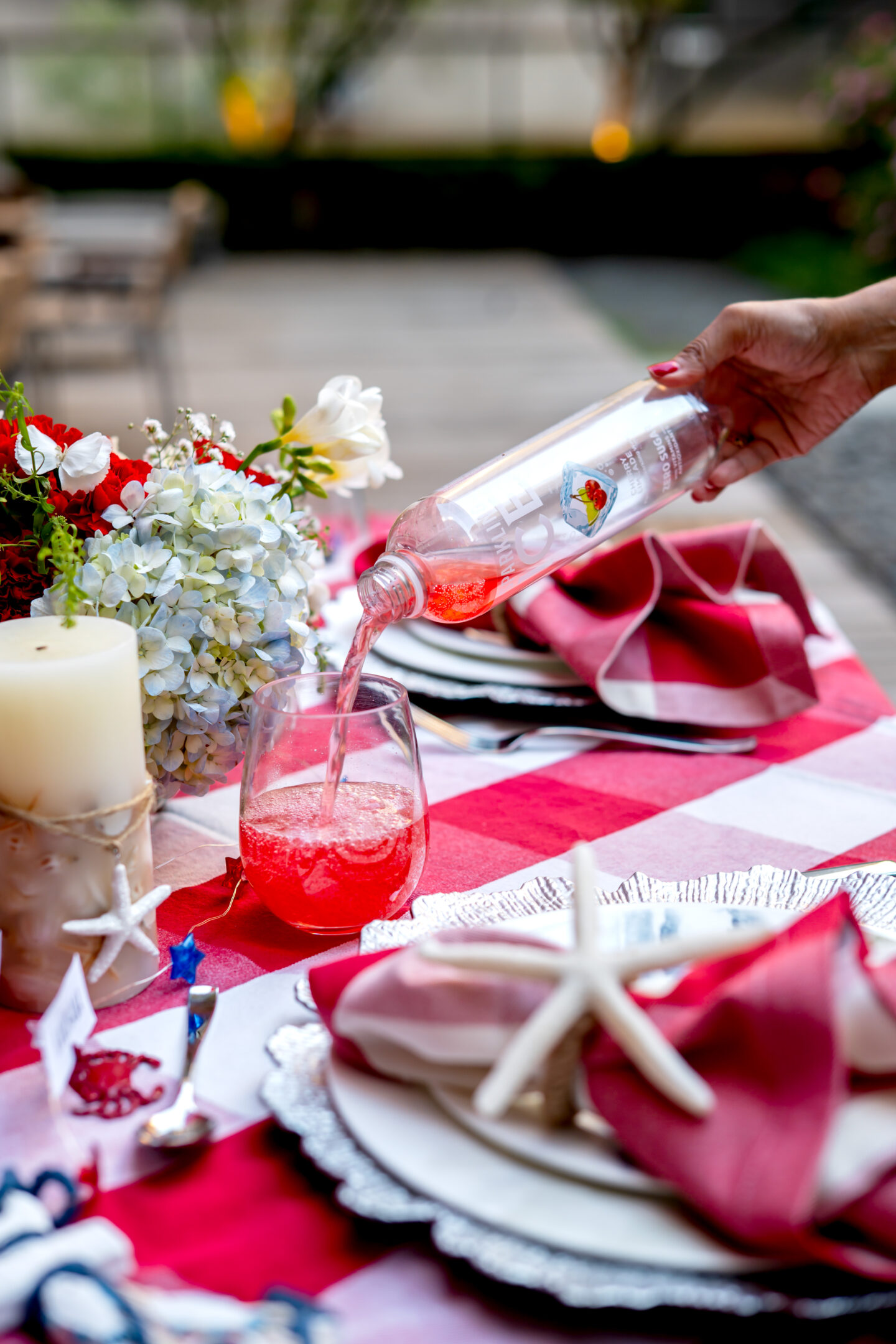 Pouring sparkling ice into a wine glass on a Red and White Gingham table 