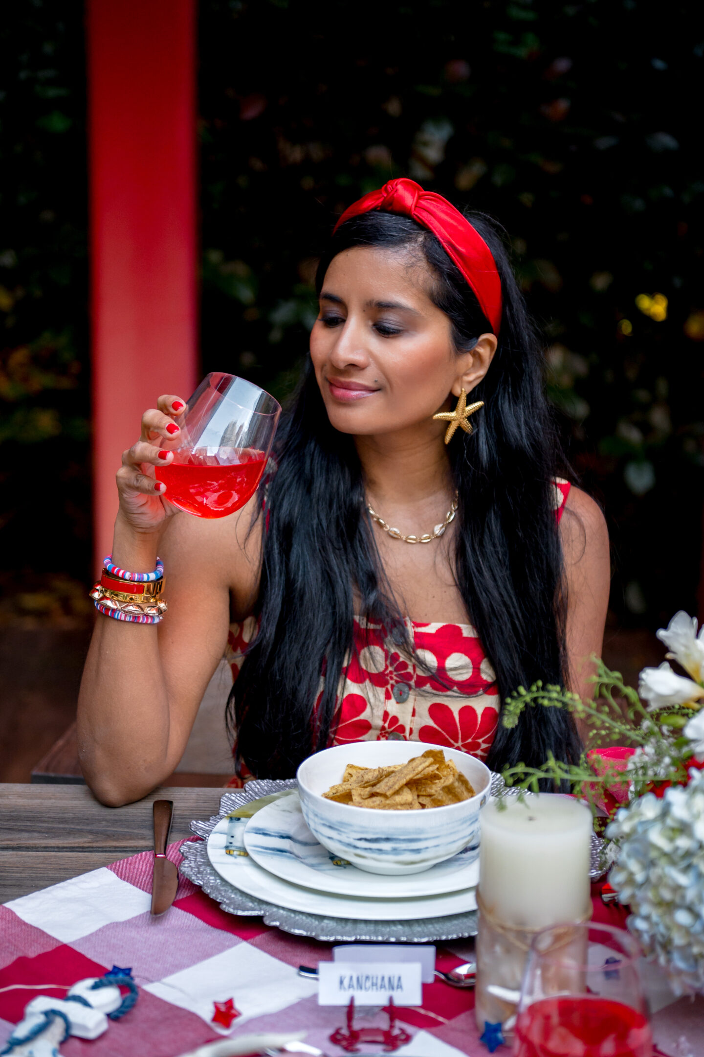 Lady drinking sparkling ice seated at a table with Red and White Gingham linens