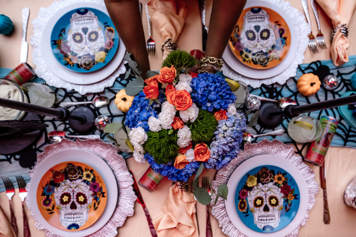 Summerween Party: Lady placing bouquet down on table with Day of the Dead plates